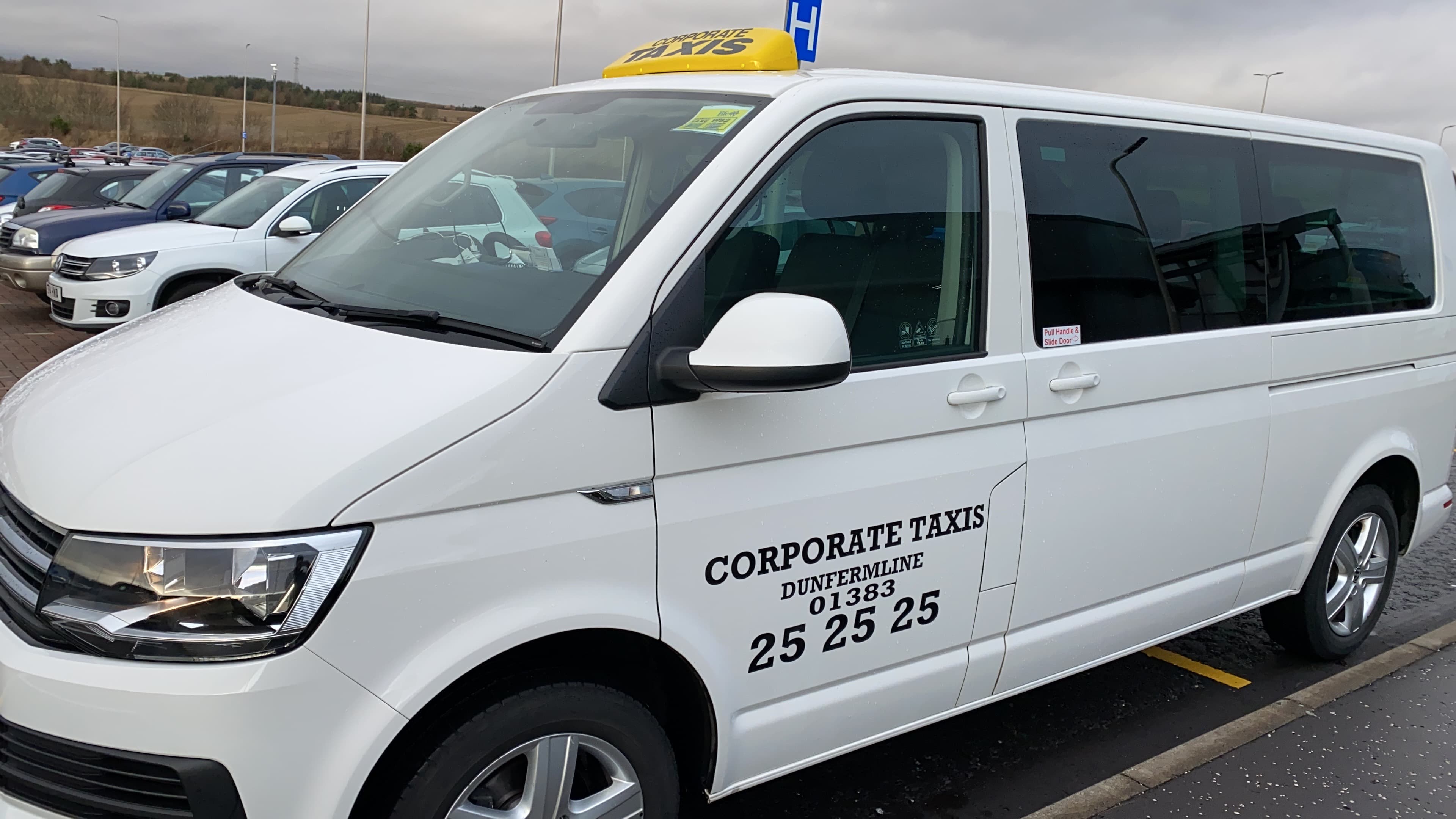 White Volkswagen Transporter taxi with Corporate Taxis Dunfermline livery and roof sign