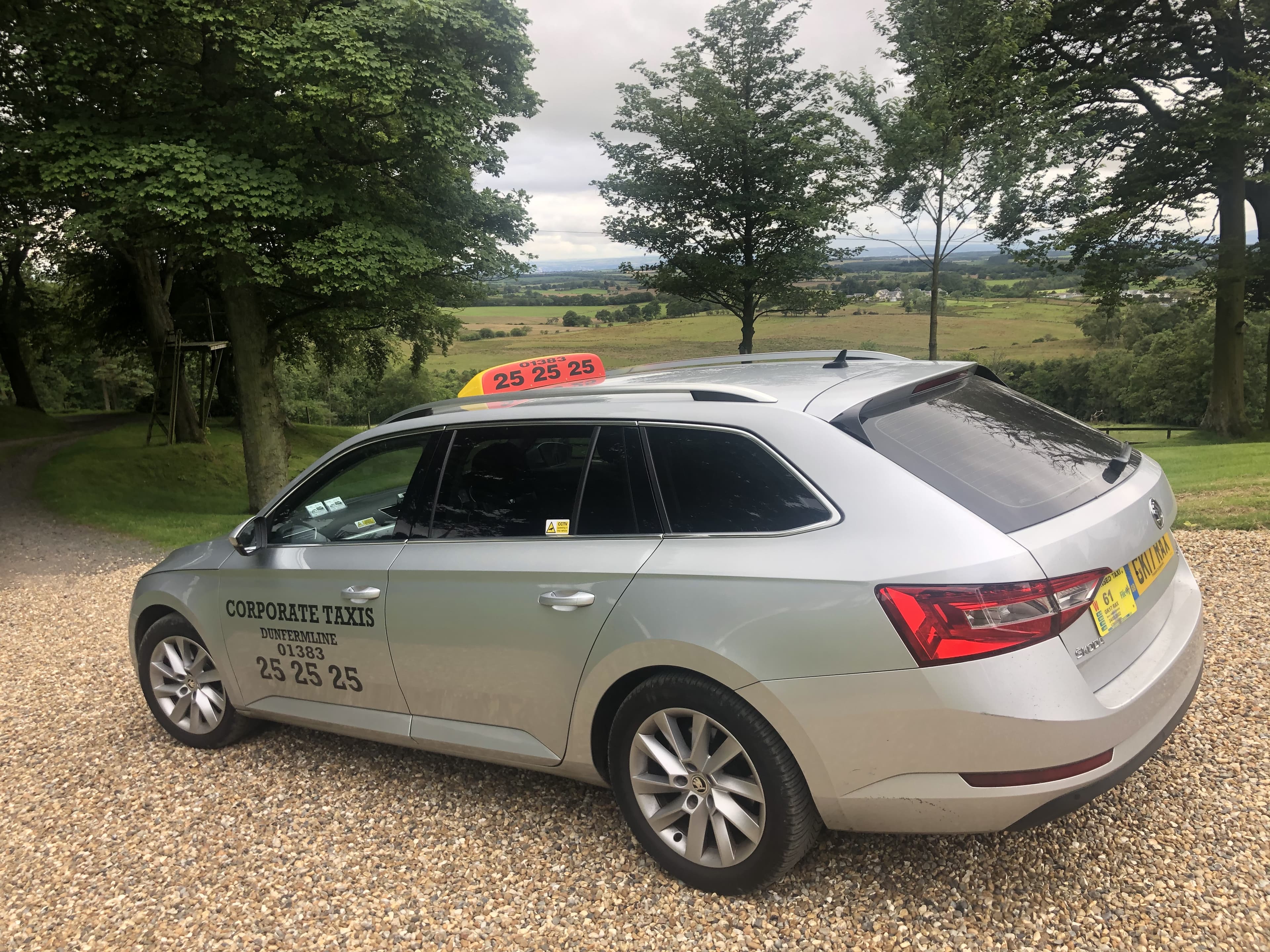 Silver Skoda Superb Estate taxi with roof sign, parked in the Scottish countryside