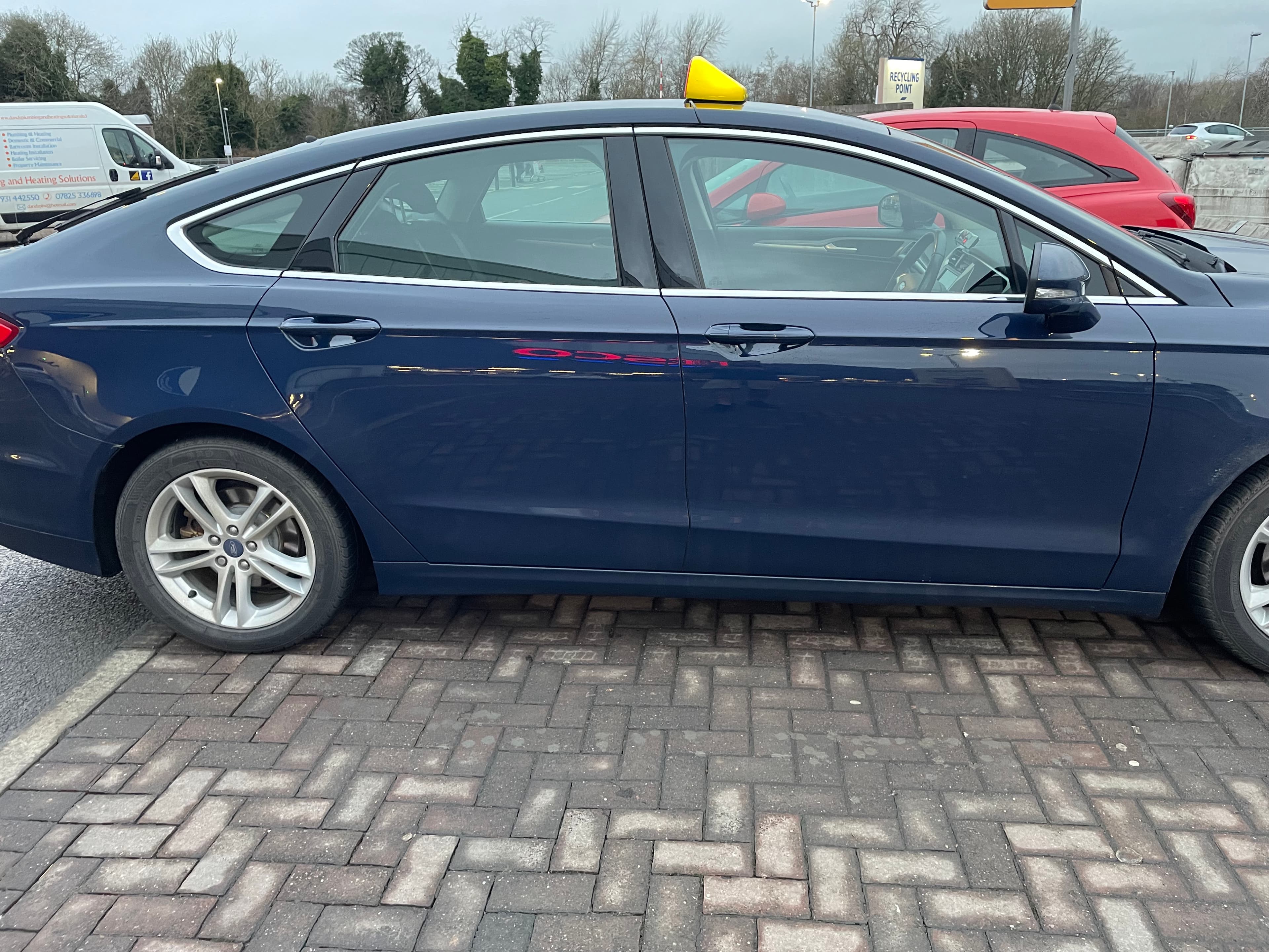 Dark blue Ford Mondeo executive taxi with roof sign in a car park